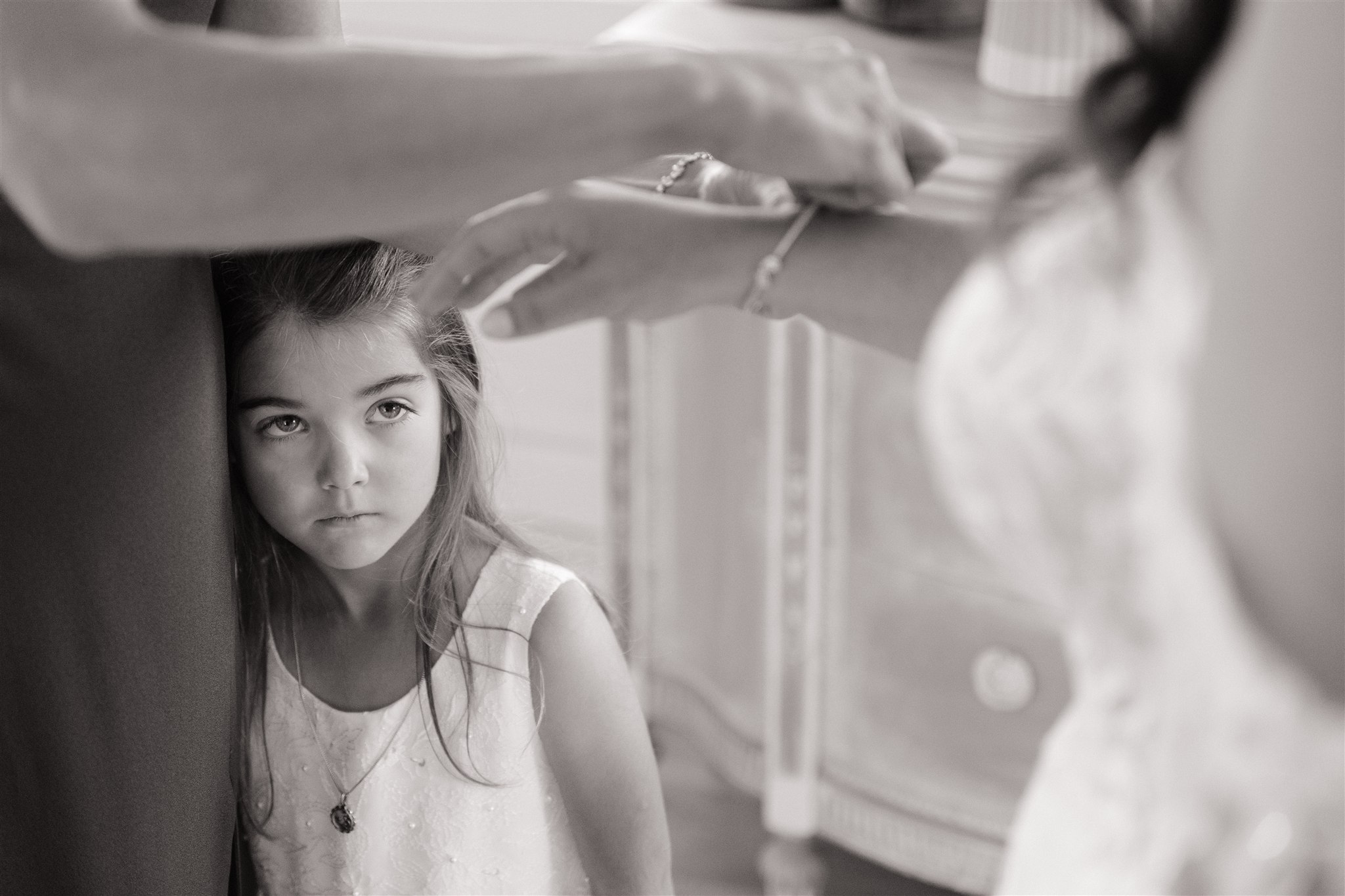 Flower girl watching on as the bride has jewelry put on her