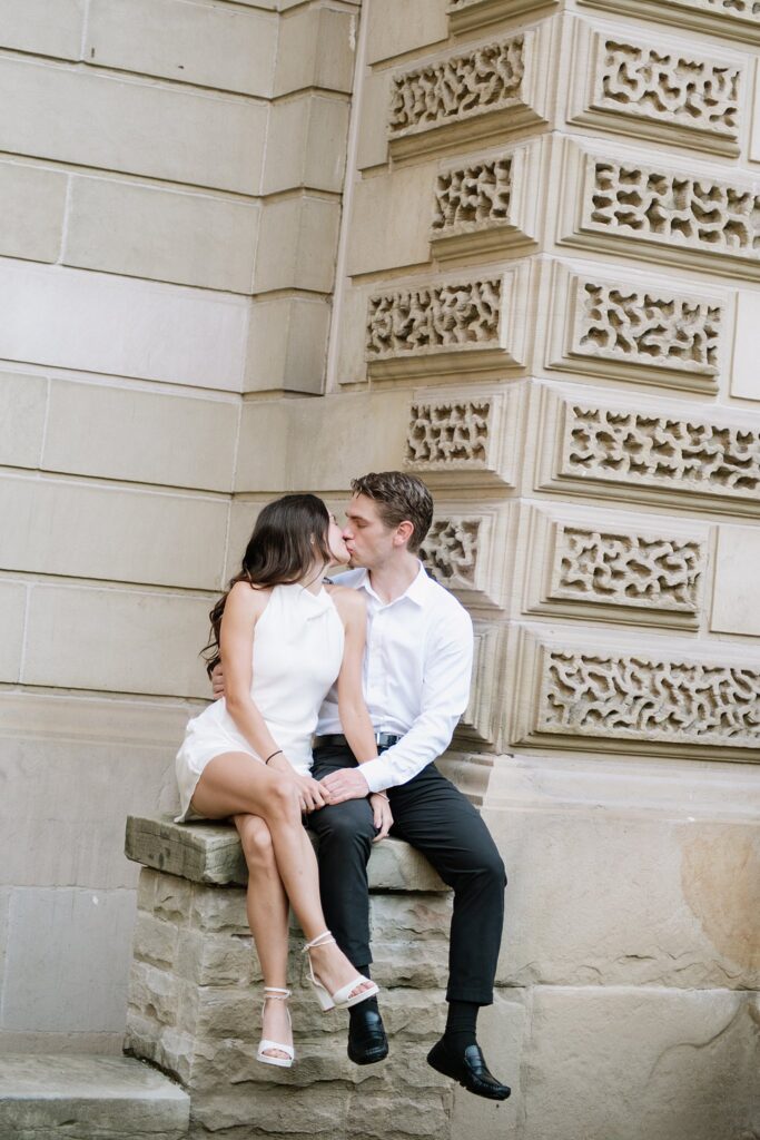Couple sharing a kiss while sitting on a set of stairs outside Osgoode Hall