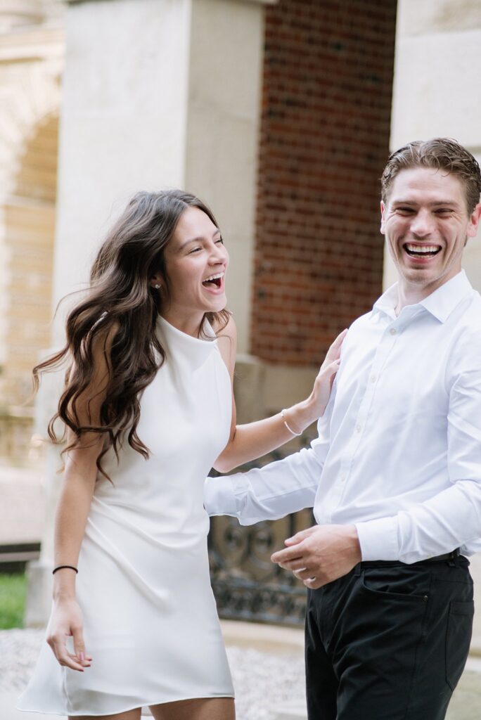 Couple laughing while taking engagement photos outside Osgoode Hall