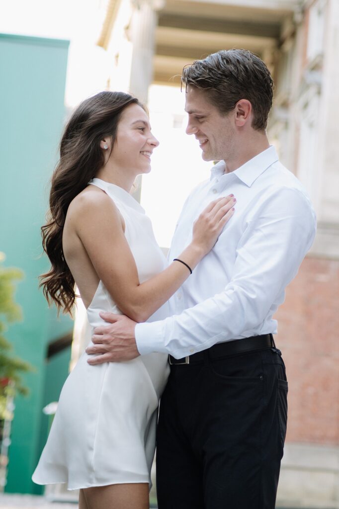 Couple smiling while taking engagement photos outside Osgoode Hall in Toronto